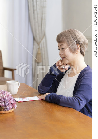 A senior woman writing the address on a gift envelope with a brush pen A senior woman writing the address on a gift envelope with a brush pen 130942949