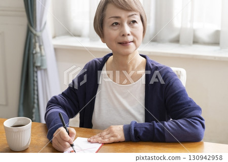 A senior woman writing the address on a gift envelope with a brush pen 130942958