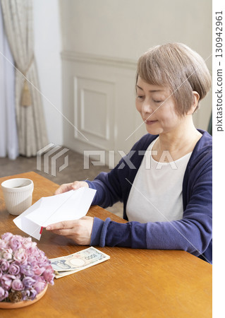 一位老年婦女用毛筆在禮物信封上寫地址 130942961