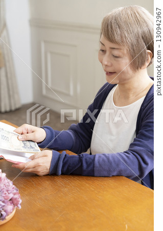 A senior woman writing the address on a gift envelope with a brush pen 130942967
