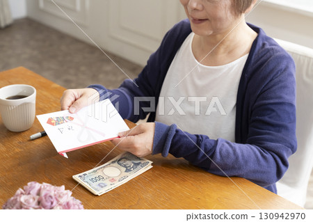A senior woman writing the address on a gift envelope with a brush pen 130942970