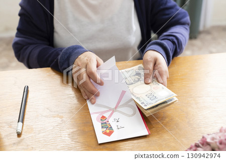 A senior woman writing the address on a gift envelope with a brush pen A senior woman writing the address on a gift envelope with a brush pen 130942974