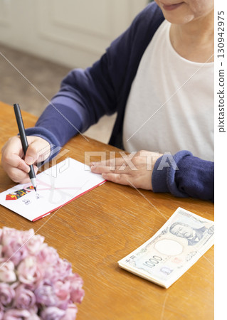A senior woman writing the address on a gift envelope with a brush pen A senior woman writing the address on a gift envelope with a brush pen 130942975
