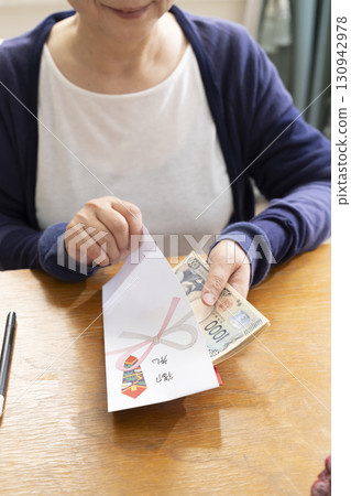 A senior woman writing the address on a gift envelope with a brush pen A senior woman writing the address on a gift envelope with a brush pen 130942978