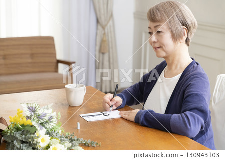 一位老年婦女用毛筆在弔唁信封上寫地址 一位老年婦女用毛筆在弔唁信封上寫地址 130943103