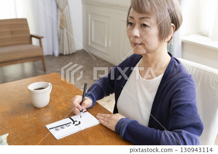 一位老年婦女用毛筆在弔唁信封上寫地址 130943114