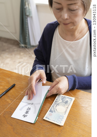 A senior woman writing the address on a condolence envelope with a brush pen 130943118