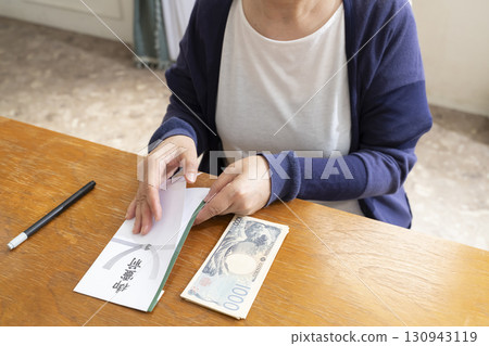 一位老年婦女用毛筆在弔唁信封上寫地址 130943119