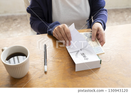 一位老年婦女用毛筆在弔唁信封上寫地址 130943120