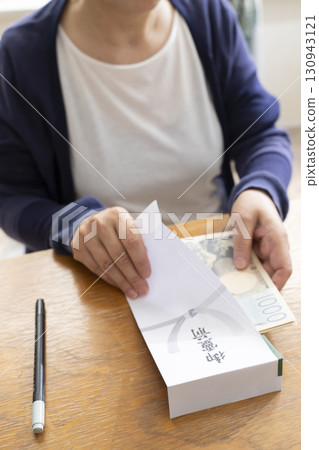 A senior woman writing the address on a condolence envelope with a brush pen A senior woman writing the address on a condolence envelope with a brush pen 130943121
