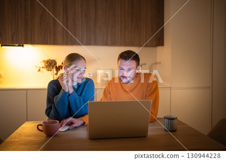 Engaged couple choosing hotel together on laptop in evening while planning vacation trip at home 130944228
