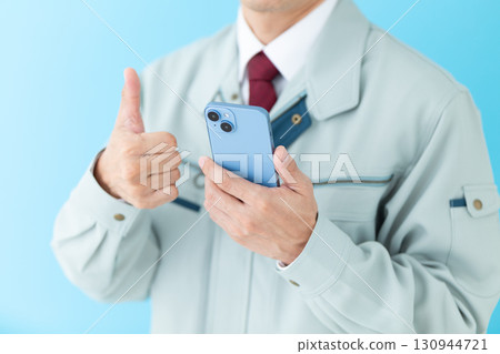 一位身著工作服的中年男性商人拿著智慧型手機豎起大拇指 一位身著工作服的中年男性商人拿著智慧型手機豎起大拇指 130944721