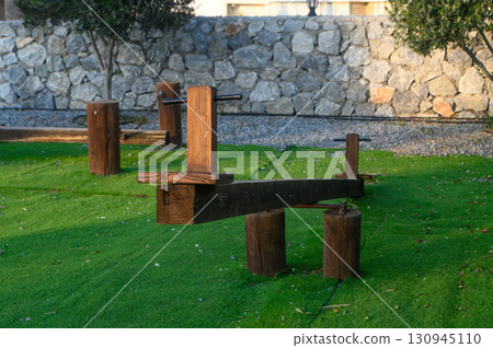 Unique wooden fitness equipment nestled in a serene outdoor park setting under the morning sunlight 130945110