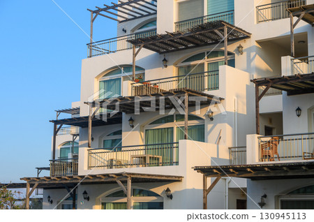 Charming coastal architecture with sunlit balconies inviting relaxation at a seaside retreat 130945113
