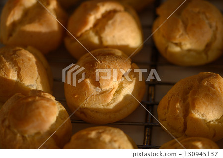 Golden pastries cooling on a wire rack in a warm kitchen during sunny afternoon 130945137