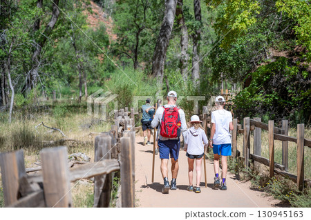 Family enjoys hiking together on a sunny day in a beautiful natural park setting 130945163