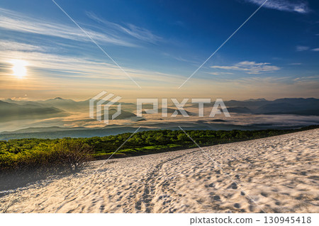 Snow remaining on the summer mountain trail and mountains enveloped in a sea of clouds 130945418