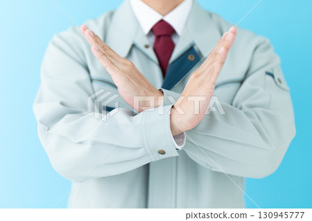 A middle-aged male businessman in work clothes making a cross sign A middle-aged male businessman in work clothes making a cross sign 130945777