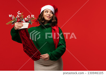 Woman in green sweater and Santa hat looking to side Woman in green sweater and Santa hat looking to side 130946105