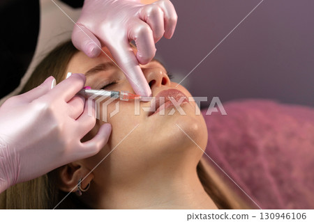 Aesthetician injects lip filler into patient's right upper lip Aesthetician injects lip filler into patient's right upper lip 130946106