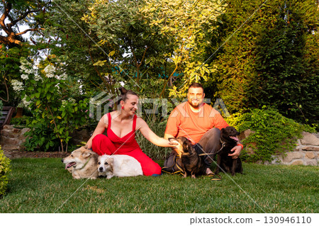 Happy couple enjoying garden time with four dogs at sunset 130946110