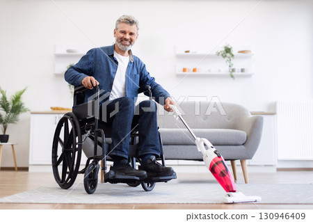 Middle-aged white man in wheelchair vacuuming carpet in modern living room, smiling, teamwork Middle-aged white man in wheelchair vacuuming carpet in modern living room, smiling, teamwork 130946409