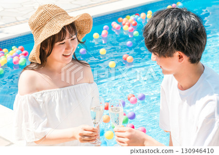 Couple toasting with champagne glasses by the pool at a resort hotel on vacation 130946410