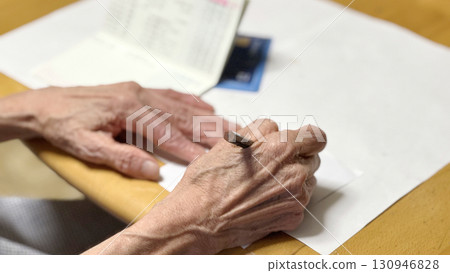 一位老婦人打開存摺並用鉛筆寫字的手 130946828
