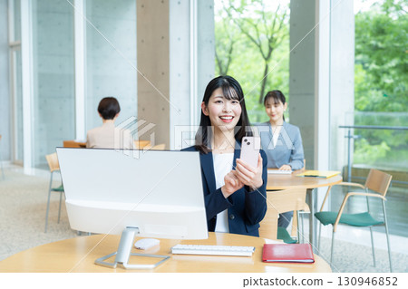 經營一部智能手機的女商人在辦公室 130946852