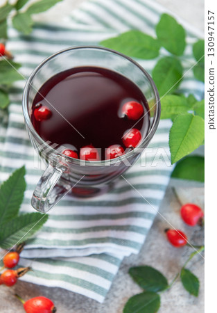 Rosehip tea brewing in glass cup with fresh rose hips and leaves Rosehip tea brewing in glass cup with fresh rose hips and leaves 130947157
