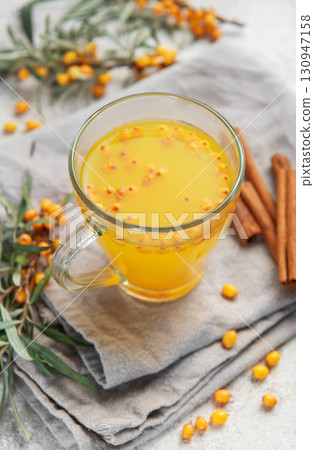 Sea buckthorn tea with berries and cinnamon sticks on grey napkins 130947158