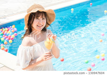 Young Asian woman drinking tropical juice by the pool (resort, vacation, vacation) 130947604