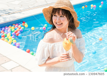 年輕的亞洲女性在泳池邊喝熱帶果汁（度假村、度假、假期） 130947605