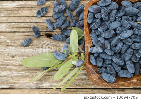 Fresh Blue Honeysuckle Berries in a Wooden Bowl on Rustic Wooden Background Fresh Blue Honeysuckle Berries in a Wooden Bowl on Rustic Wooden Background 130947709