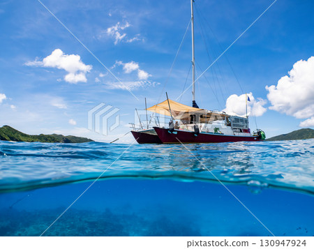 Partially submerged shot of a catamaran yacht diving cruise ship. Beautiful coral reefs and schools of tropical fish. Kera, Shimajiri District, Okinawa Prefecture 130947924