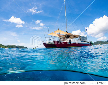 一艘雙體遊艇潛水遊輪的部分水下照片。美麗的珊瑚礁和成群的熱帶魚。沖繩縣島尻喀拉 130947925