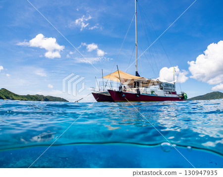 Partially submerged shot of a catamaran yacht diving cruise ship. Beautiful coral reefs and schools of tropical fish. Kera, Shimajiri District, Okinawa Prefecture 130947935