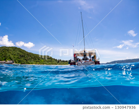 Partially submerged shot of a catamaran yacht diving cruise ship. Beautiful coral reefs and schools of tropical fish. Kera, Shimajiri District, Okinawa Prefecture 130947936