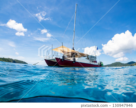一艘雙體遊艇潛水遊輪的部分水下照片。美麗的珊瑚礁和成群的熱帶魚。沖繩縣島尻喀拉 一艘雙體遊艇潛水遊輪的部分水下照片。美麗的珊瑚礁和成群的熱帶魚。沖繩縣島尻喀拉 130947946