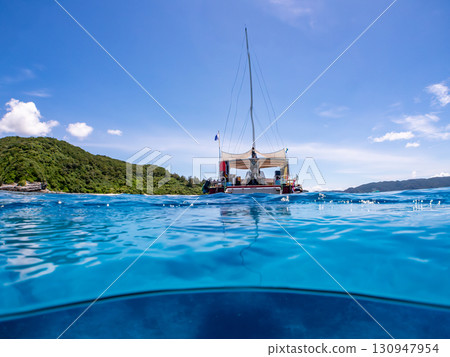 Partially submerged shot of a catamaran yacht diving cruise ship. Beautiful coral reefs and schools of tropical fish. Kera, Shimajiri District, Okinawa Prefecture 130947954