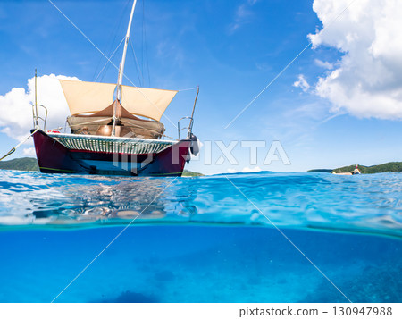 一艘雙體遊艇潛水遊輪的部分水下照片。美麗的珊瑚礁和成群的熱帶魚。沖繩縣島尻喀拉 一艘雙體遊艇潛水遊輪的部分水下照片。美麗的珊瑚礁和成群的熱帶魚。沖繩縣島尻喀拉 130947988