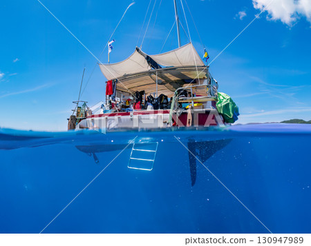 一艘雙體遊艇潛水遊輪的部分水下照片。美麗的珊瑚礁和成群的熱帶魚。沖繩縣島尻喀拉 130947989