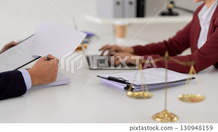 Adult professionals collaborate legal documents at modern office Lawyers consult business contract details using laptop paperwork justice fairness 130948159