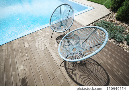 Stylish summer scene of two outdoor chairs beside clean pool Stylish summer scene of two outdoor chairs beside clean pool 130949354
