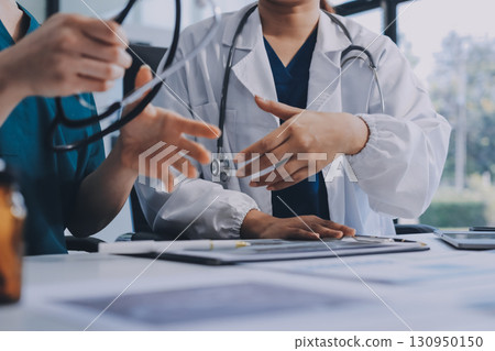 Medical team meeting analyzing blood test results in hospital laboratory. Doctors and scientists in lab coats are having a discussion about blood test result, holding test tubes and taking notes. 130950150