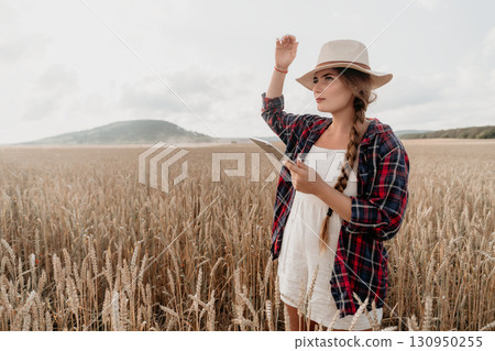 Young Woman in a Wheat Field Using a Tablet Young Woman in a Wheat Field Using a Tablet 130950255