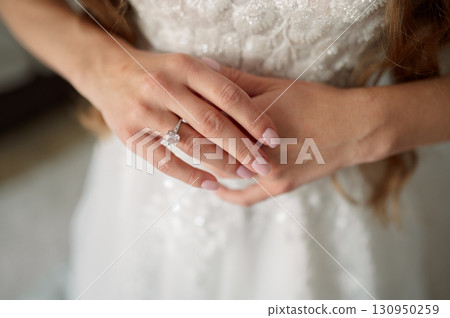 Bride wearing a stunning white wedding dress, proudly showcasing a dazzling diamond engagement ring, love symbolizing commitment Bride wearing a stunning white wedding dress, proudly showcasing a dazzling diamond engagement ring, love symbolizing commitment 130950259