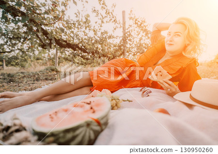 Woman Relaxing on a Picnic Blanket with Watermelon 130950260