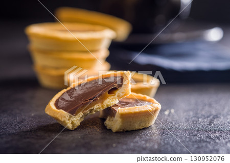 Sweet chocolate tartelettes on black table. 130952076