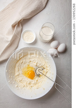 Bowl with cream cheese and egg for kneading dough. Ingredients for cooking Basque Spanish burnt Saint Sebastian cheesecake. Cream cheese, sugar, eggs, flour and cream. Recipe step by step Bowl with cream cheese and egg for kneading dough. Ingredients for cooking Basque Spanish burnt Saint Sebastian cheesecake. Cream cheese, sugar, eggs, flour and cream. Recipe step by step 130952268